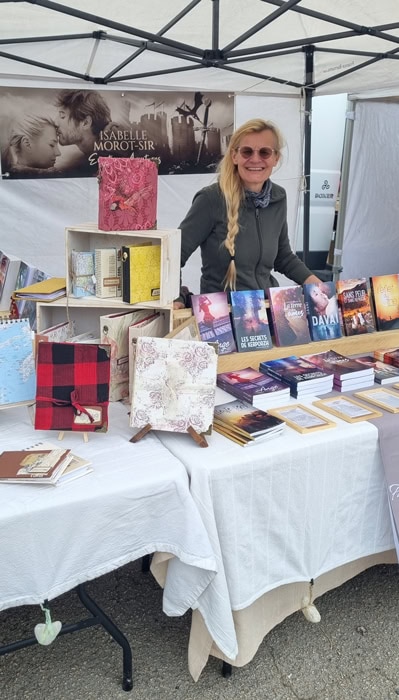 Isabelle Morot-Sir présente ses romans et ses carnets sur son stand lors d'un marché en Bretagne.