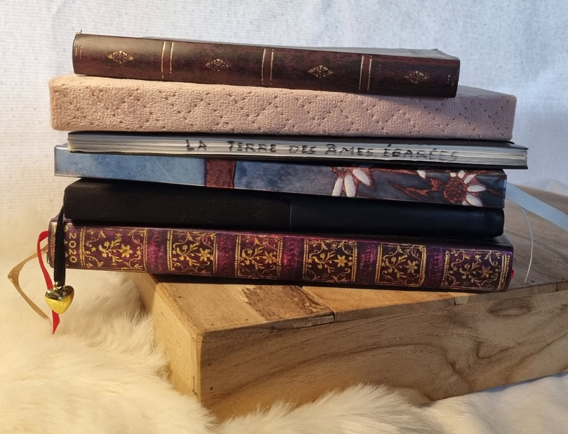 Pile de livres et carnets anciens posés sur une caisse en bois.