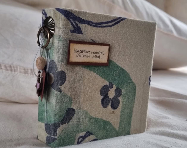 Petit carnet artisanal fait main recouvert de tissu aux motifs verts et bleus.